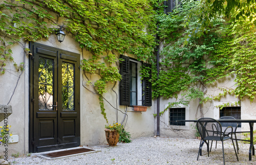Facade of a house facing its courtyard with its walls covered by ivy