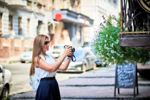 Young woman takes snapshot with a digital camera on the city street