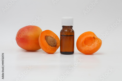 Apricot oil bottle with ripe apricots and apricot kernels isolated white