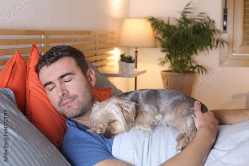 Cute man sharing bed with small dog