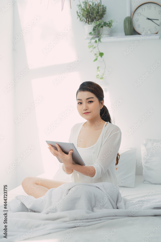 pretty woman with digital tablet sitting in bed at home pretty woman with digital tablet sitting in bed at home