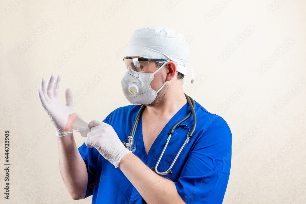 Doctor in blue uniform and medical mask. Fools around with gloves. Doctor in blue uniform and medical mask. Fools around with gloves.