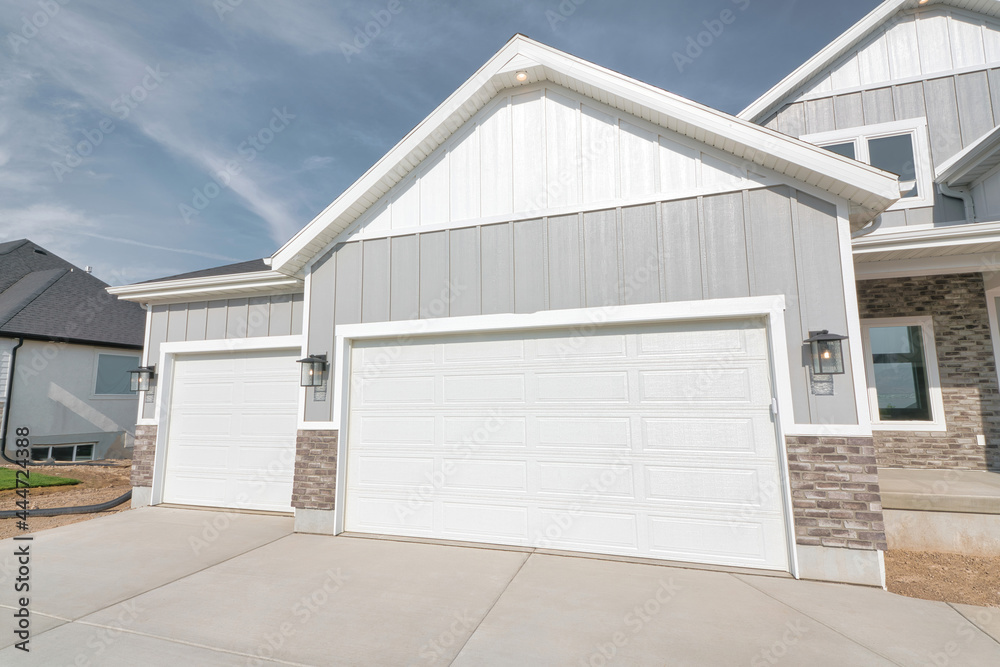 Entry to two car garage with white doors of house against blue sky background