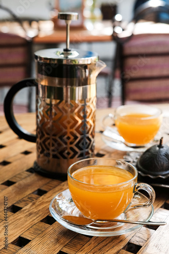 Close up view on french press and cups with sea buckthorn tea on the table.