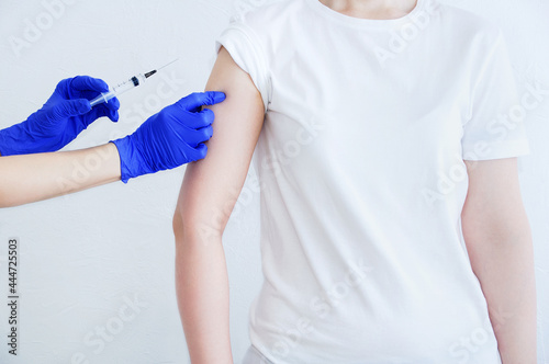 Doctor hands in medical gloves and syringe. Vaccinating a Caucasian woman patient.