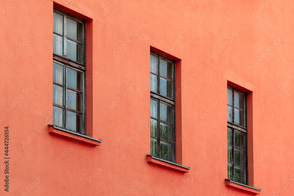 A row of old windows on the red wall