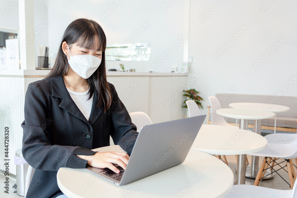 Asian woman wear mask and using laptop in coffee shop. Asian woman wear mask and using laptop in coffee shop.