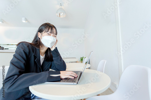 Asian woman wear mask and using laptop in coffee shop.