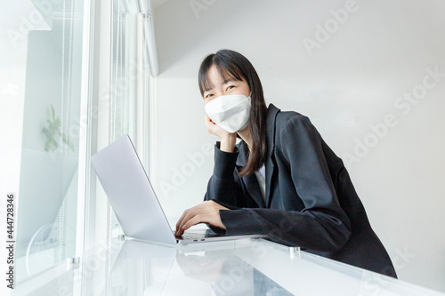 Asian woman wear mask and using laptop in coffee shop.