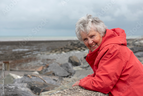 Happy, smiling senior woman on a rocky beach on a cloudy day