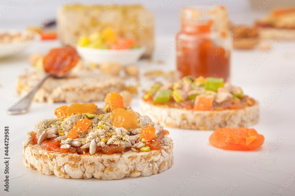 Puffed exploded wheat grains with peeled sunflower seeds, halva and raisins on a thin layer of apricot jam on a background of oriental sweets on a white wooden table