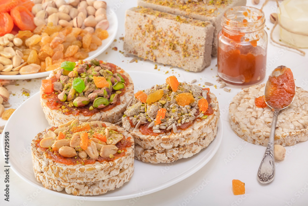 Puffed exploded wheat grains with peanuts and dried apricots, pistachios and sunflower seeds, halva and raisins on a layer of apricot jam on a white plate against a background of oriental sweets. Puffed exploded wheat grains with peanuts and dried apricots, pistachios and sunflower seeds, halva and raisins on a layer of apricot jam on a white plate against a background of oriental sweets.