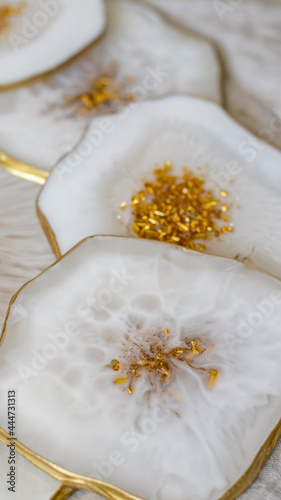 Cup holder  epoxy resin tray  stone cut  white marble with gold trim. White streaks of paint. Table setting decor  object aesthetics. Gloss  reflection. Stone effect. Blurred background. 