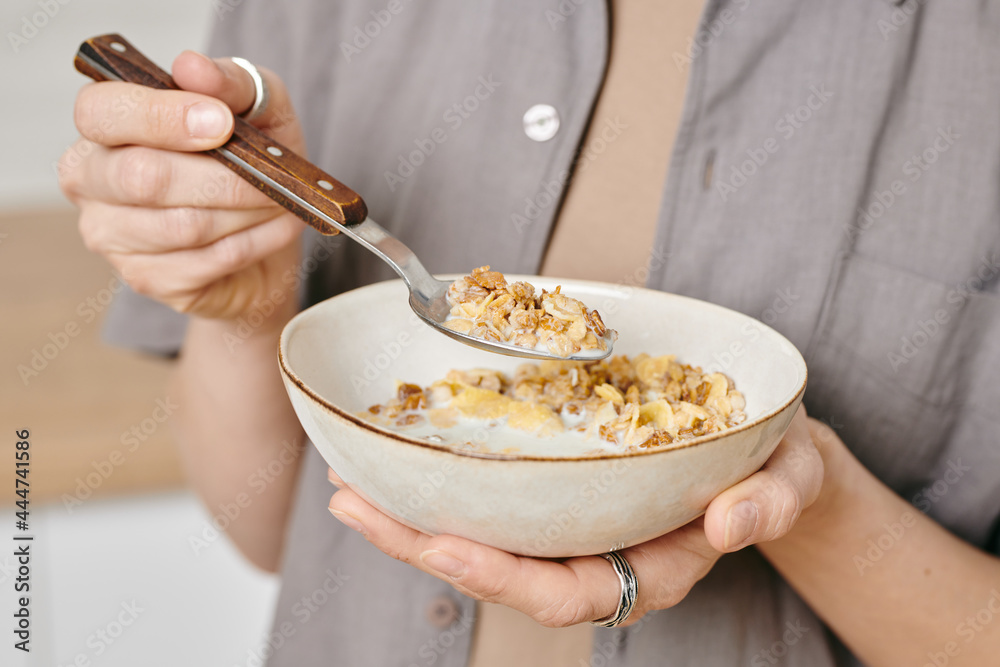 Hands of female holding bowl with muesli and spoon Hands of female holding bowl with muesli and spoon