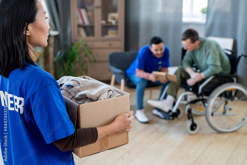 Obraz premium Asian female volunteer carrying box with folded clothes