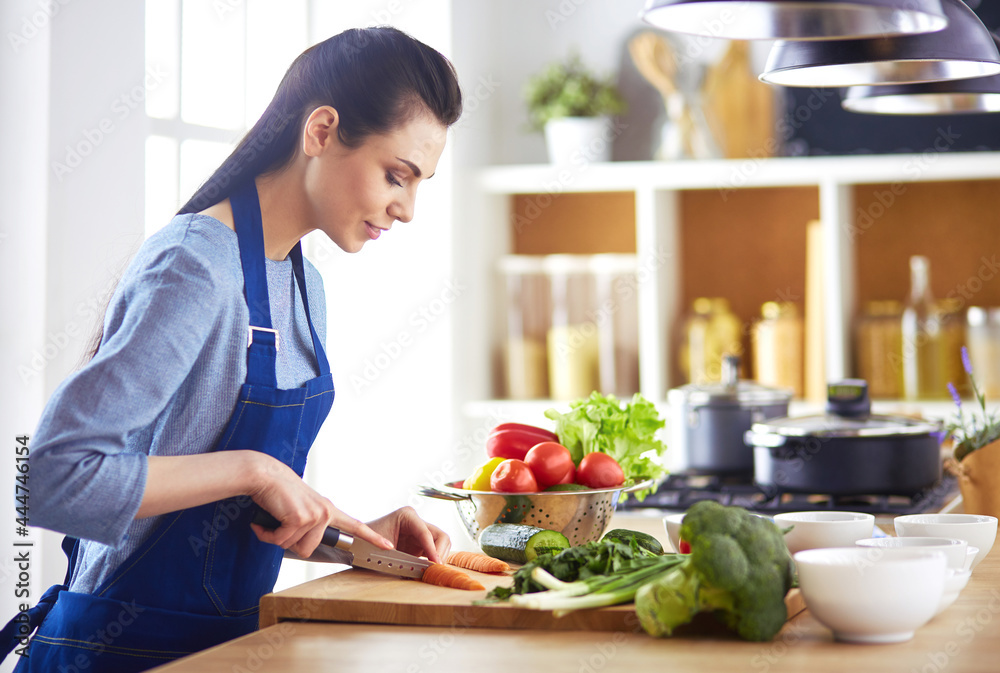 Young woman cutting vegetables in kitchen at home Young woman cutting vegetables in kitchen at home