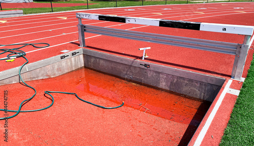 Empty steeplechase pit being filled up with water on a track