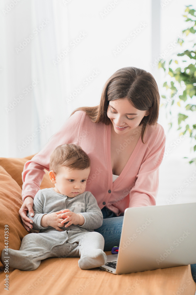 Vertical portrait of a single young mother watching cartoons with toddler newborn baby infant, developing skills imagination, self-developing programmes, e-learning, maternity leave. Freelance job Vertical portrait of a single young mother watching cartoons with toddler newborn baby infant, developing skills imagination, self-developing programmes, e-learning, maternity leave. Freelance job