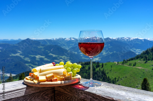 fresch tirol cheese with wine and grapes over mountain landscape photo