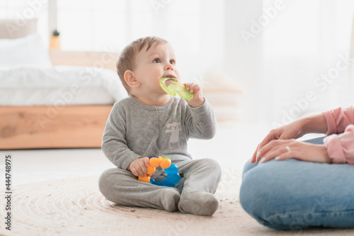 Small little kid child toddler infant newborn baby gnawing toy ring. Teething process, milk baby teeth tooth concept. Playing games with child. Babycare and motherhood