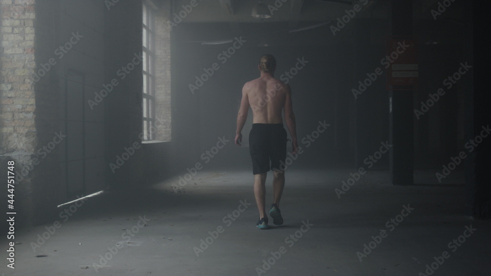 Fototapeta premium Man walking in building after workout. Athlete warming hands before training 