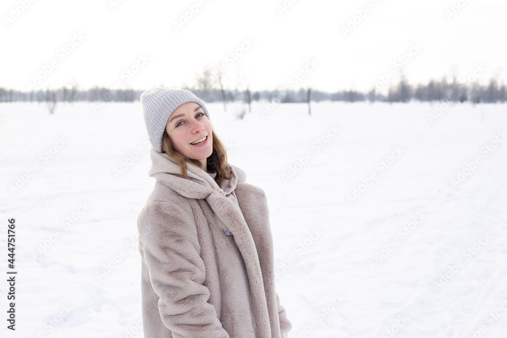 Young girl in beige clothes, fur coat made of artificial fur walks in winter Young girl in beige clothes, fur coat made of artificial fur walks in winter