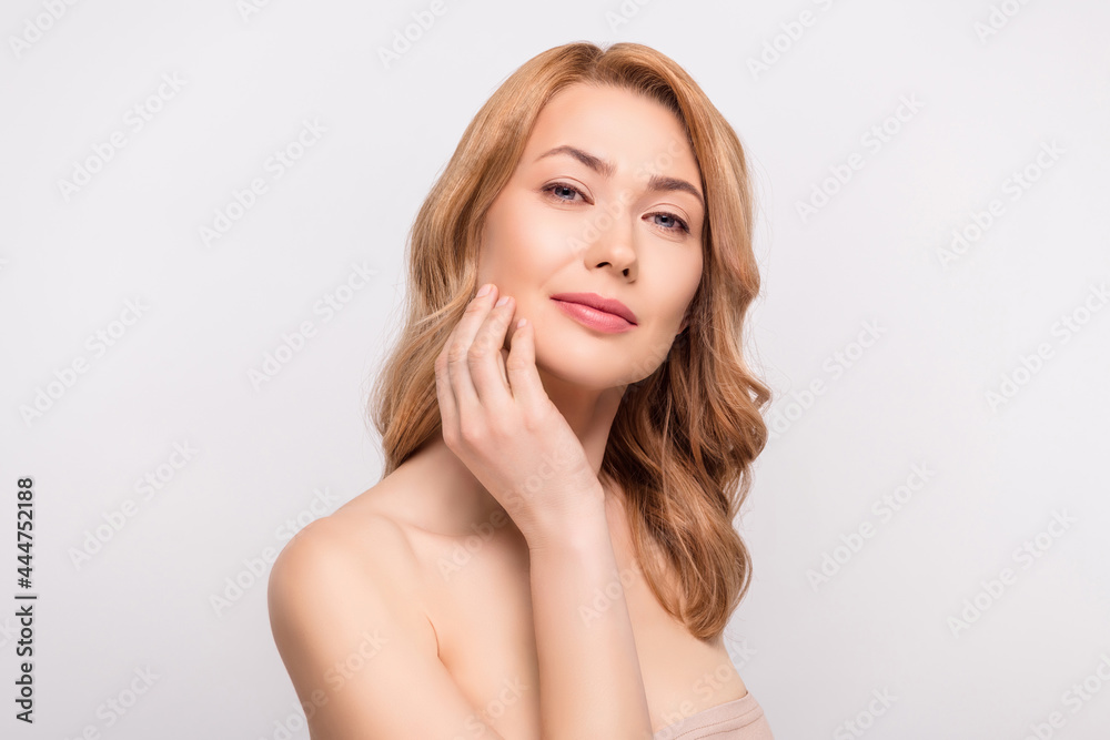 Photo portrait woman naked shoulders applying cream on face isolated white color background Photo portrait woman naked shoulders applying cream on face isolated white color background