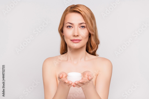 Portrait of attractive woman holding on palms new hyaluronic bio cream fresh skin isolated over grey pastel color background
