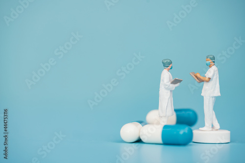 Miniature support team, Doctor emergency medical team wear surgical mask with pills and blue sea background. Health care, life insurance for covid-19 concept. Report and data science