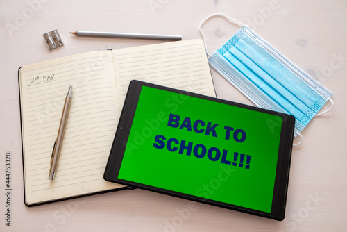 Notebook, pen, pencil, template, tablet with "back to school" text on the screen. Beginning of the school year and distancing. 