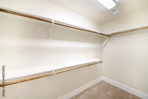 Empty walk-in closet with white walls and carpeted floor
