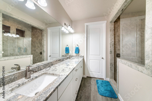 Bathroom with long vanity with two sinks and walk-in shower with half wall and glass