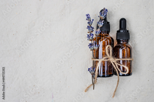 Cosmetic bottles made of brown glass with lavender oil on a white background.