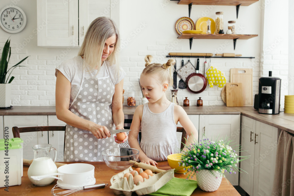 Cute little girl helps mom bake cookies in the kitchen Cute little girl helps mom bake cookies in the kitchen