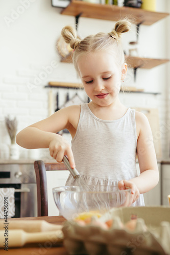 Cute little girl helps mom bake cookies in the kitchen