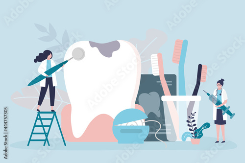 Dentist team examines and treats huge tooth. Female specialist with dental mirror checks tooth for caries. Various oral hygiene items. Dentistry, dental care concept.