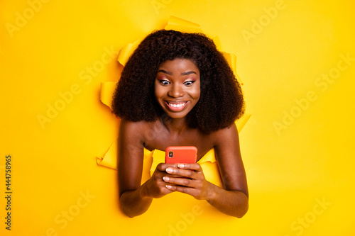 Photo of surprised amazed lady hold telephone look screen toothy smile isolated ripped yellow color background