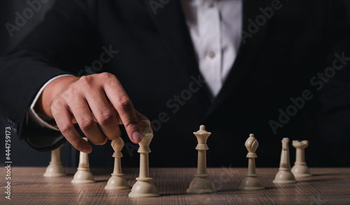 hand of businessman wearing suit moving chess figure in competition success play. strategy,teamwork, management or leadership concept.