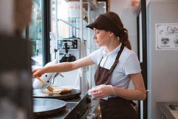 Portrait woman chef baking pancakes in an apron uniform. Fast food service of the city. fast food restaurant is a small business.