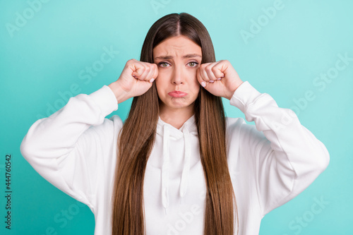 Photo of unhappy upset young woman cry bad mood hold hands face tears isolated on teal color background