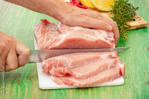 Manos con cuchillo cortando filetes de un trozo de carne fresca photo