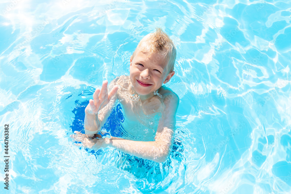 happy baby boy swimming in the blue water pool, the concept of summer holidays and school holidays