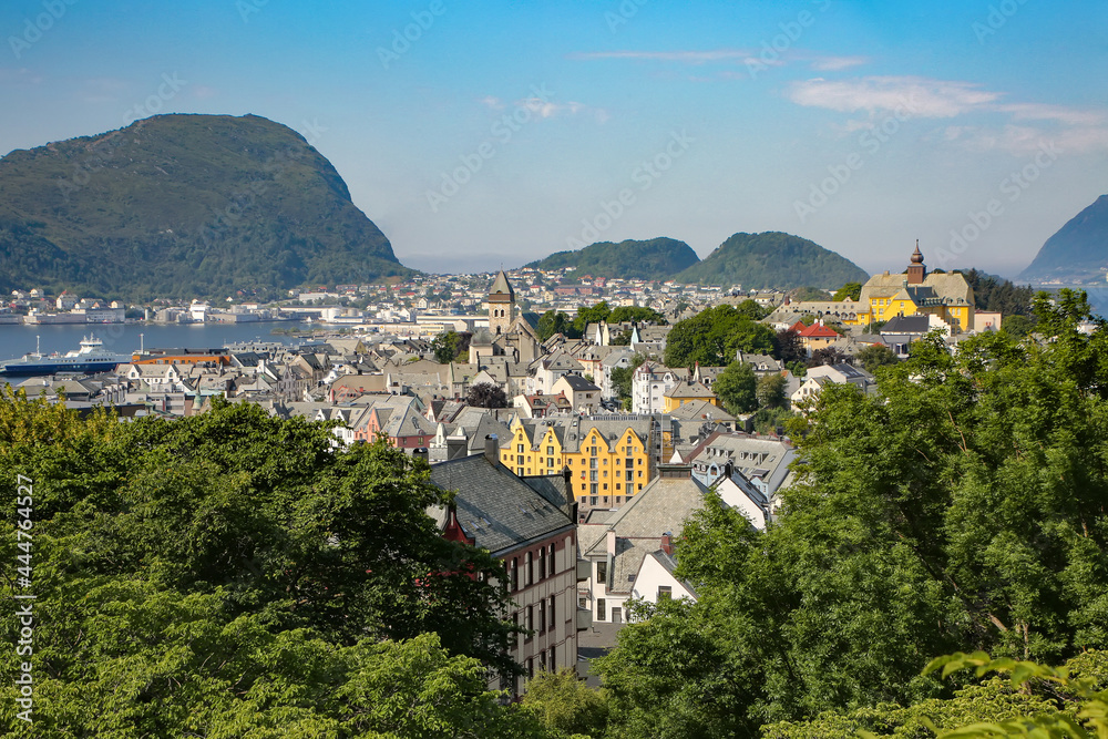 View of Alesund; Panoramic view of the archipelago, the beautiful town centre with buildings surrounded by trees, art nouveau architecture and fjords from the viewpoint Aksla, Alesund, Norway.