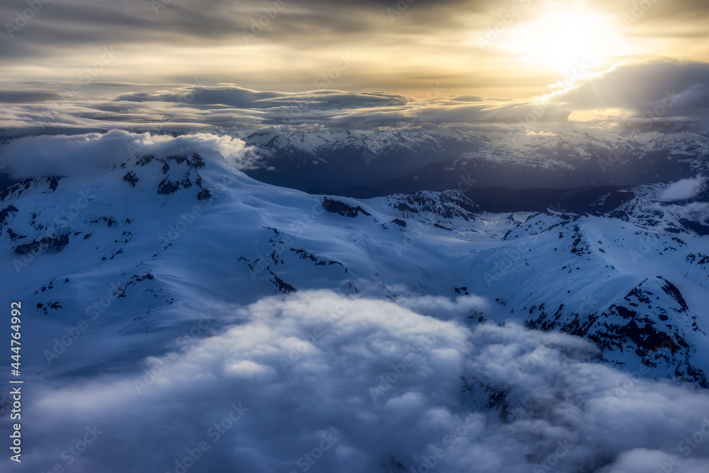 Fototapeta premium Aerial View from Airplane of Canadian Mountain Landscape in Spring time. Colorful Sunset Sky Artistic Render. North of Vancouver, British Columbia, Canada.