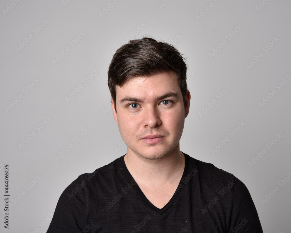 Close up head and shoulders portrait of a brunette. young man with a variety of expressive facial expressions. Isolated on a light grey studio background.