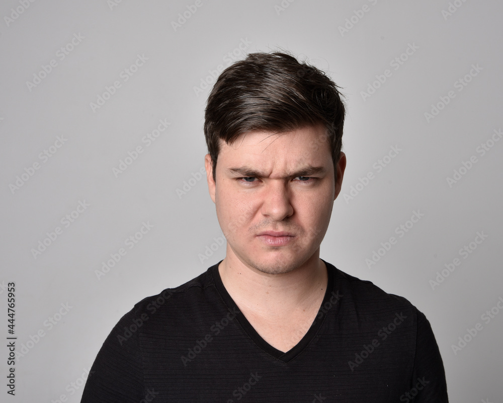Close up head and shoulders portrait of a brunette. young man with a variety of expressive facial expressions. Isolated on a light grey studio background. Close up head and shoulders portrait of a brunette. young man with a variety of expressive facial expressions. Isolated on a light grey studio background.
