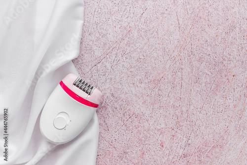 White epilator on soft silk. Hair removal and depilatory concept photo