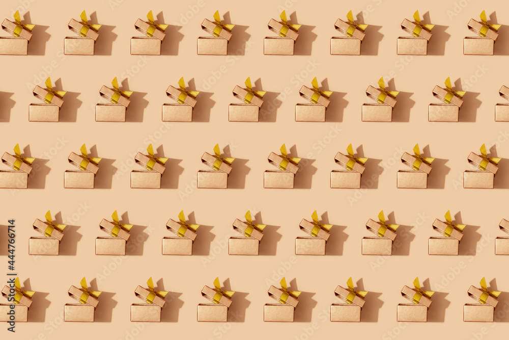 Pattern of golden holiday boxes with ribbon on a yellow background. Festive pattern background.