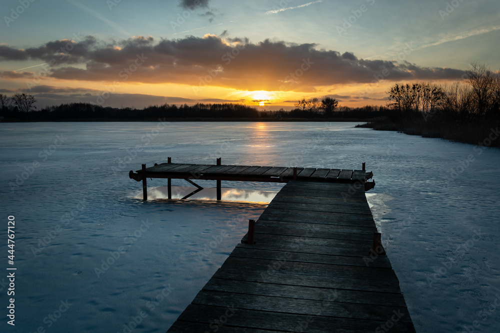 A pier on a frozen lake and a beautiful sunset