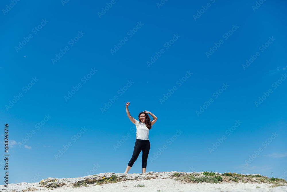 woman standing on a cliff looking at the sky of the journey woman standing on a cliff looking at the sky of the journey